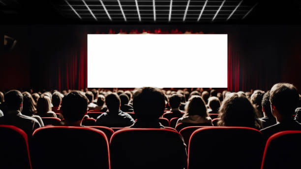 A large audience attentively watching a 123Movies for Free in a dimly lit theater, with screens illuminating their faces.